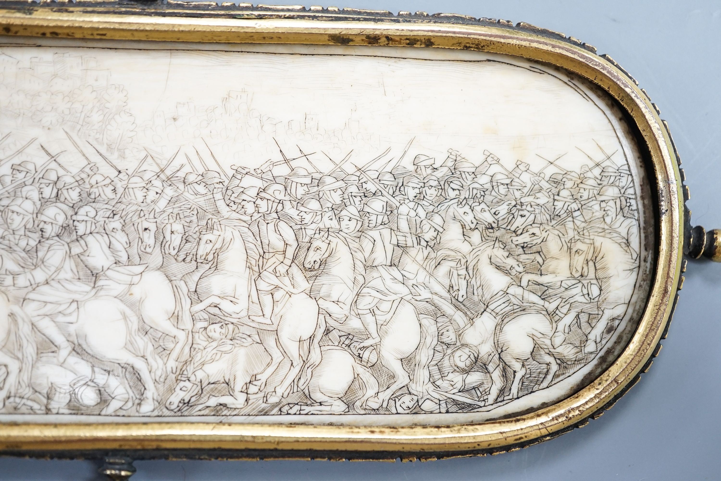 A 17th century French oval ivory plaque in a revolving metal surround, etched on both sides with battle scenes and ships in the background 17cm